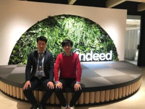 Author sits with team member in the lobby of an Indeed office with a living wall in the background