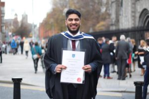 Hamaad in graduation robe holding degree